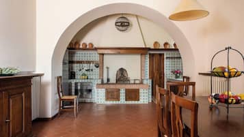 Una cocina con un arco, una lámpara colgante y un frutero sobre un pedestal.