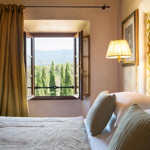 A hotel room with a bed, a window with an open shutter, a lamp, and a framed picture on the wall. - Viesca Suites & Villas Il Borro Toscana (Reggello)