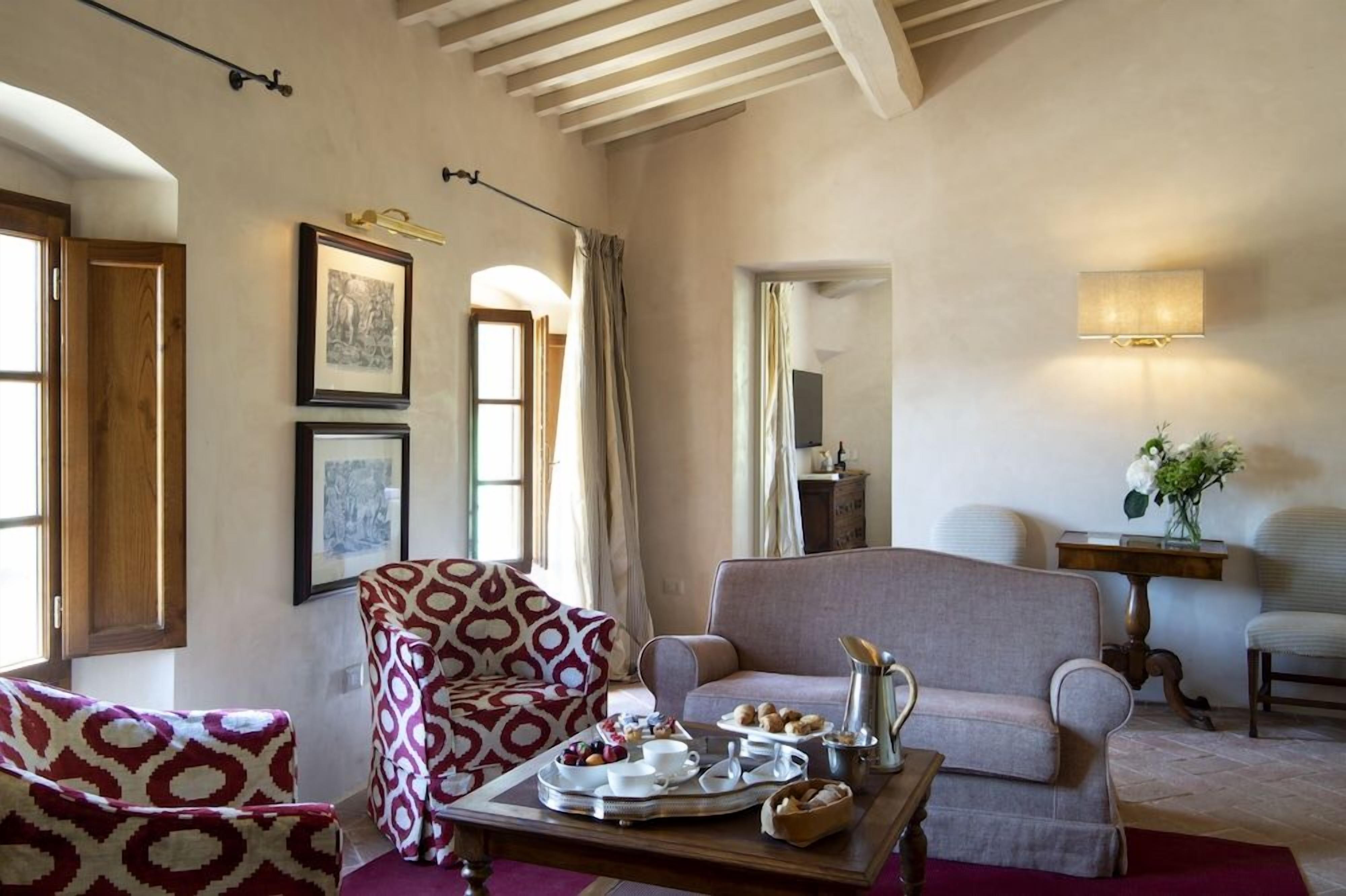 A cozy living room with a patterned armchair, a sofa, and a coffee table with breakfast items.