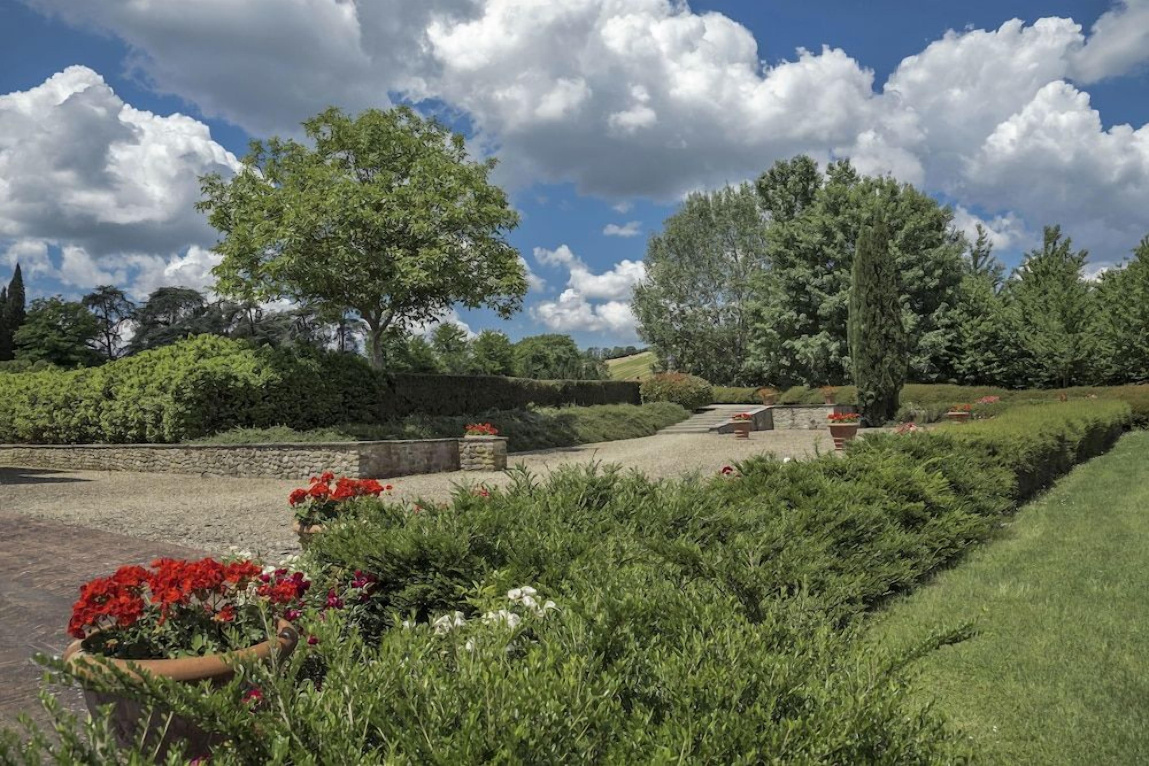 A landscaped garden with a gravel path, stone benches, and various plants.