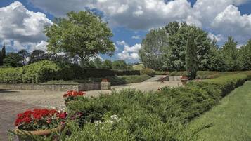 A landscaped garden with a gravel path, stone benches, and various plants.