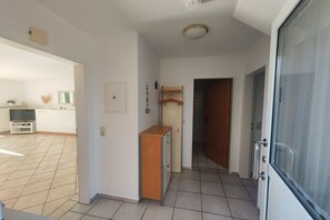 Een gang met een houten kast, een deur en een schuifdeur die naar een kamer leidt.