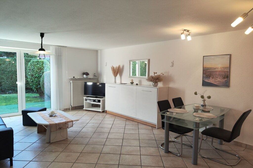 A modern kitchen with a dining area, large windows, and a view of greenery.