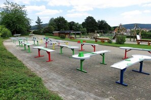 Ein Außenbereich mit mehreren in Reihen angeordneten Picknicktischen.