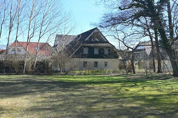 Een huis met schuin dak, omgeven door bomen en een gazon.