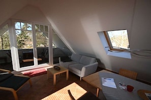 Ein Zimmer mit Esstisch, einer Couch, einem kleinen Tisch und einem Fenster.