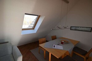 Un espace repas comprenant une table, des chaises, une fenêtre et un luminaire suspendu.