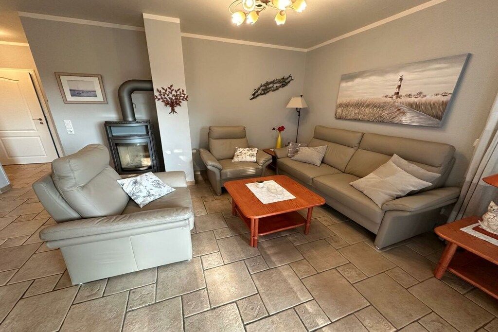 A living room with a sofa, two armchairs, a coffee table, a fireplace, and a painting on the wall.
