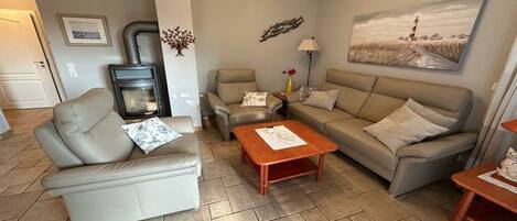 A living room with a sofa, two armchairs, a coffee table, a fireplace, and a painting on the wall.