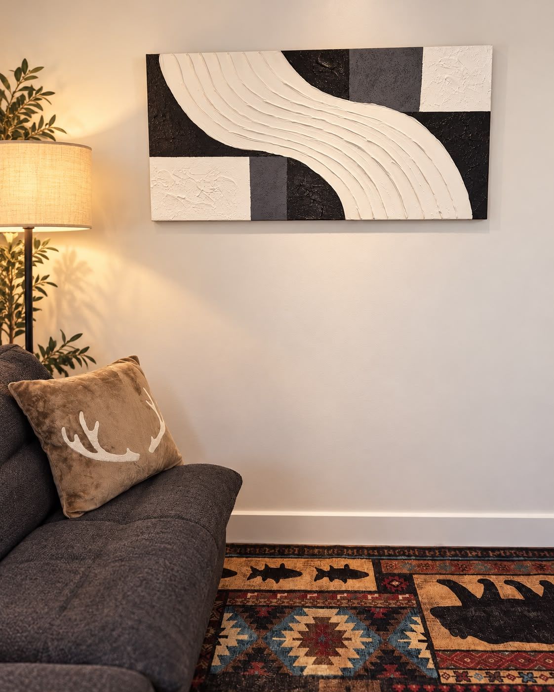 A living room with a sofa, a patterned rug, and a wall-mounted abstract artwork.