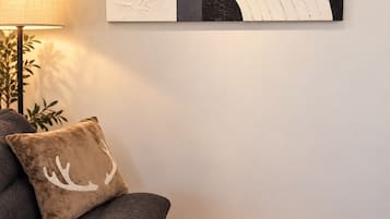 A living room with a sofa, a patterned rug, and a wall-mounted abstract artwork.