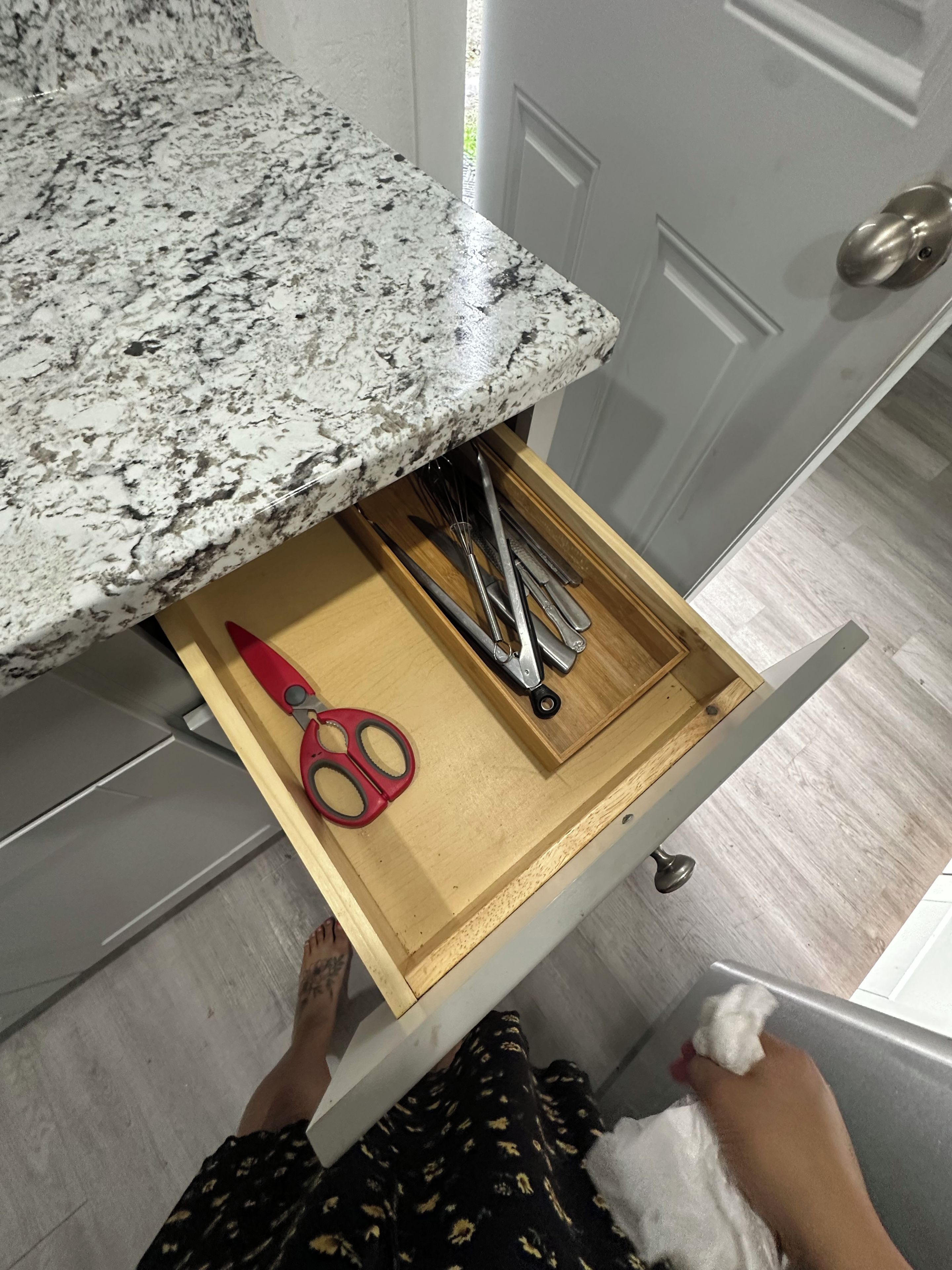 Un tiroir de cuisine contenant des ustensiles, une paire de ciseaux et une planche à découper.