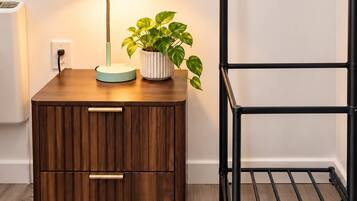 A wooden bedside table with a lamp and a potted plant.