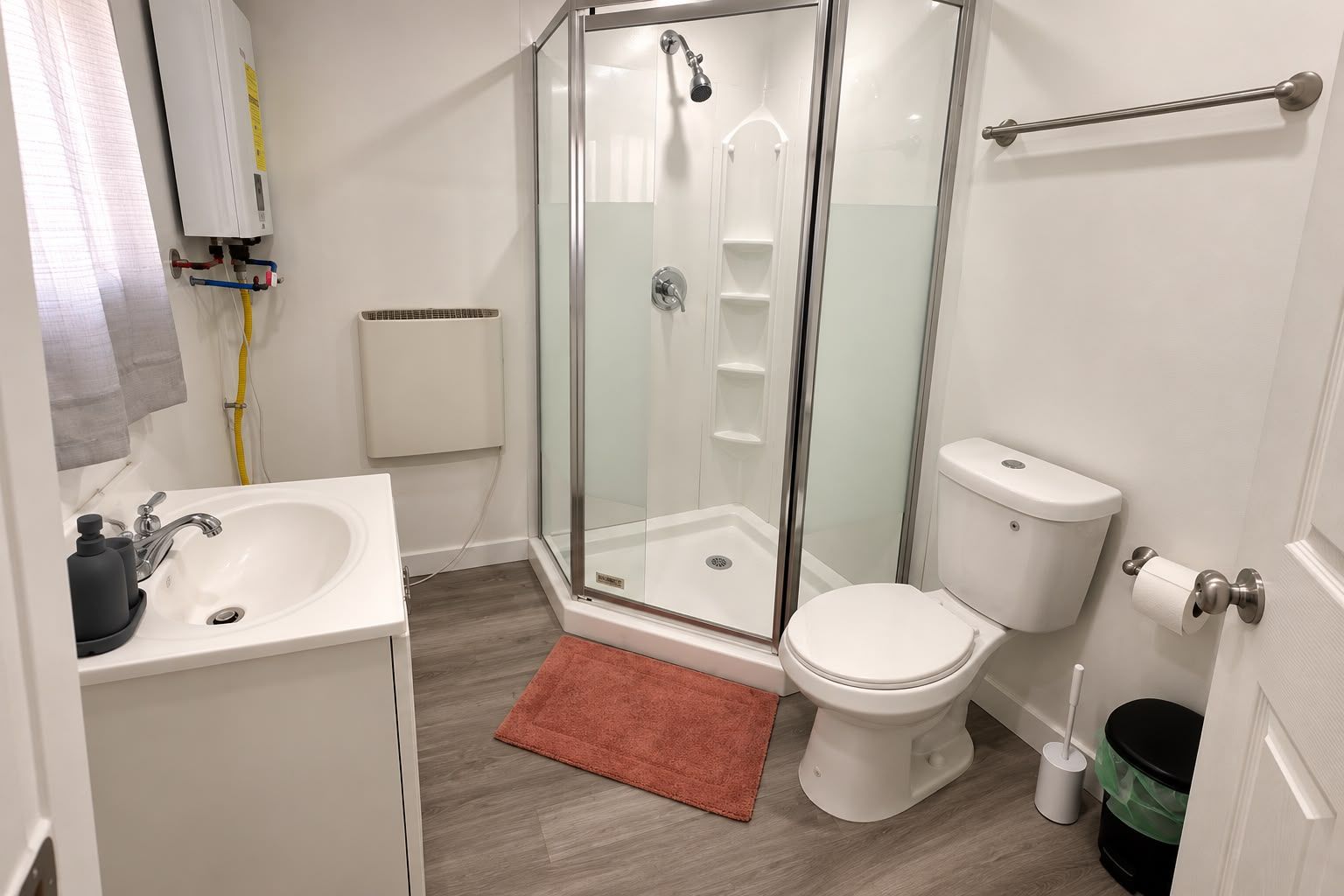 A bathroom with a glass-enclosed shower, a white sink, and a toilet.