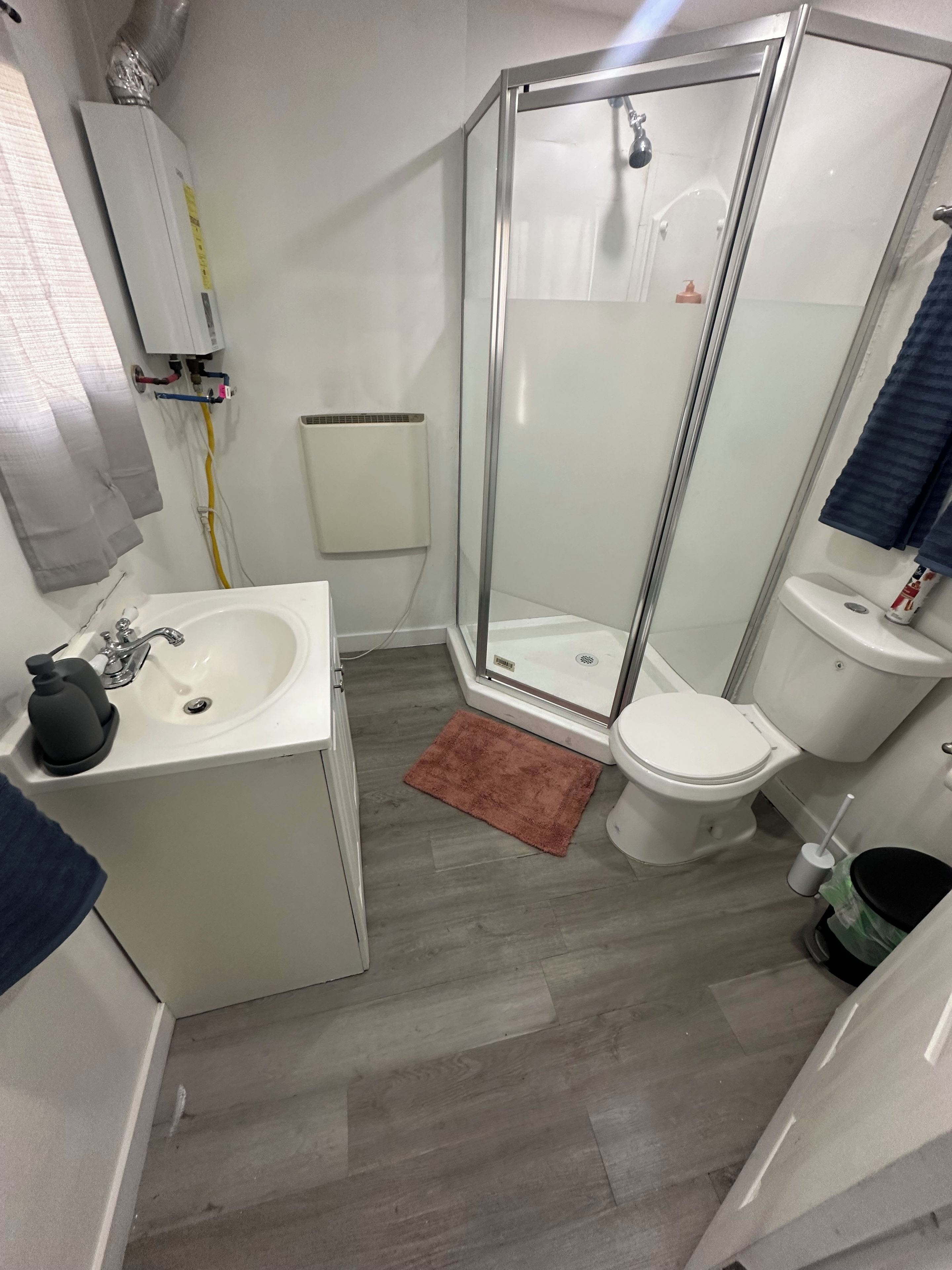 Ein Badezimmer mit Dusche, Toilette, Waschbecken und Handtuchhalter.