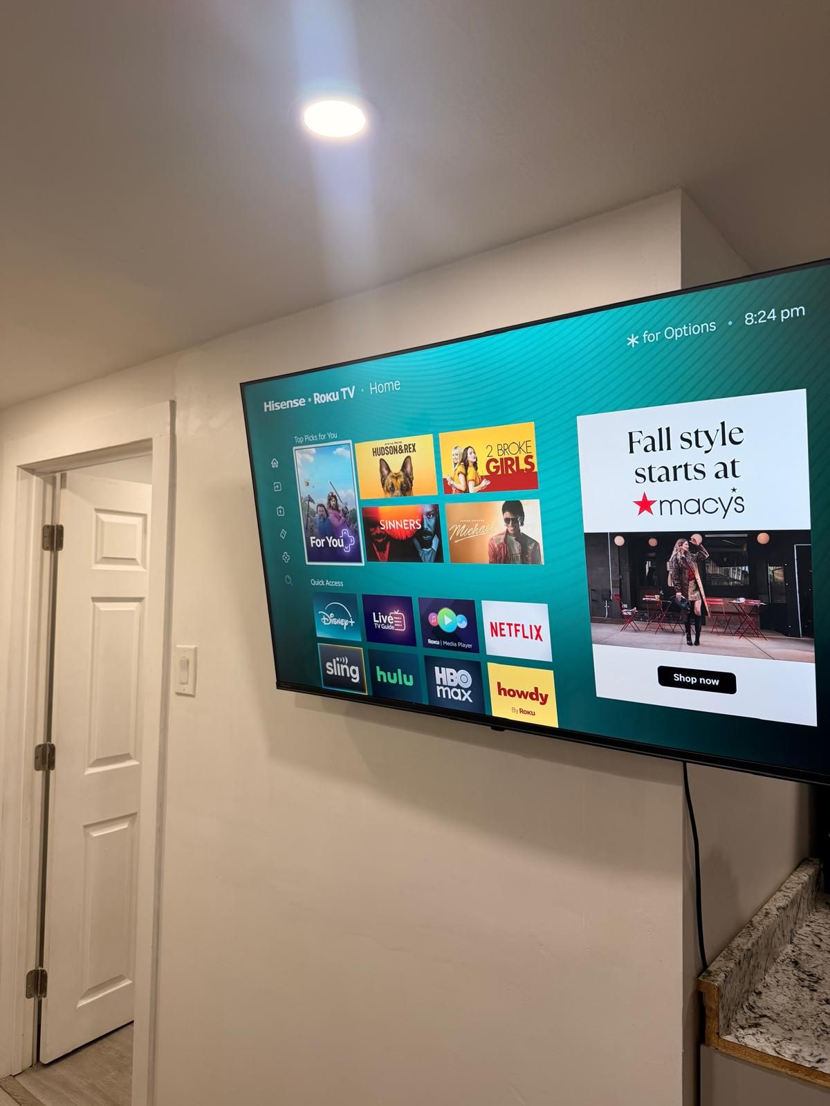 Un téléviseur à écran plat fixé au mur affiche l’interface d’un service de diffusion en continu, proposant diverses options de divertissement.
