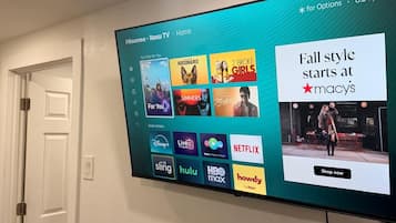 Un téléviseur à écran plat fixé au mur affiche l’interface d’un service de diffusion en continu, proposant diverses options de divertissement.