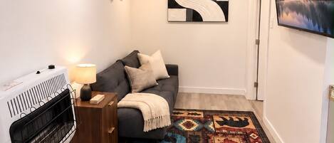 Una sala de estar moderna con chimenea, un sofá, un tapete estampado y un cuadro en la pared.