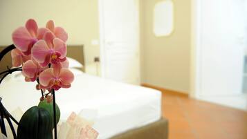 Ein Hotelzimmer mit einem Bett, einer Vase mit rosa Blumen und einer Tür im Hintergrund.