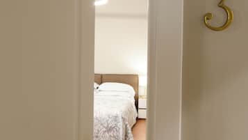 Una habitación de hotel con una cama, una mesita de noche, una lámpara y una puerta con el número 3.