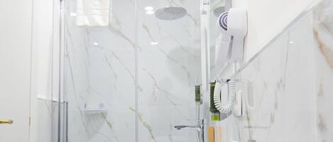 Une salle de bain moderne avec une douche à parois de verre, un lavabo blanc et un sèche-cheveux fixé au mur.