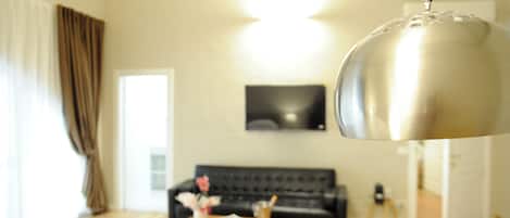 A living room with a sofa, a coffee table, and a television mounted on the wall.