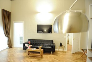 A living room with a black leather sofa, a wooden coffee table, and a large floor lamp. - Residenze Strozzi Firenze (Florence)