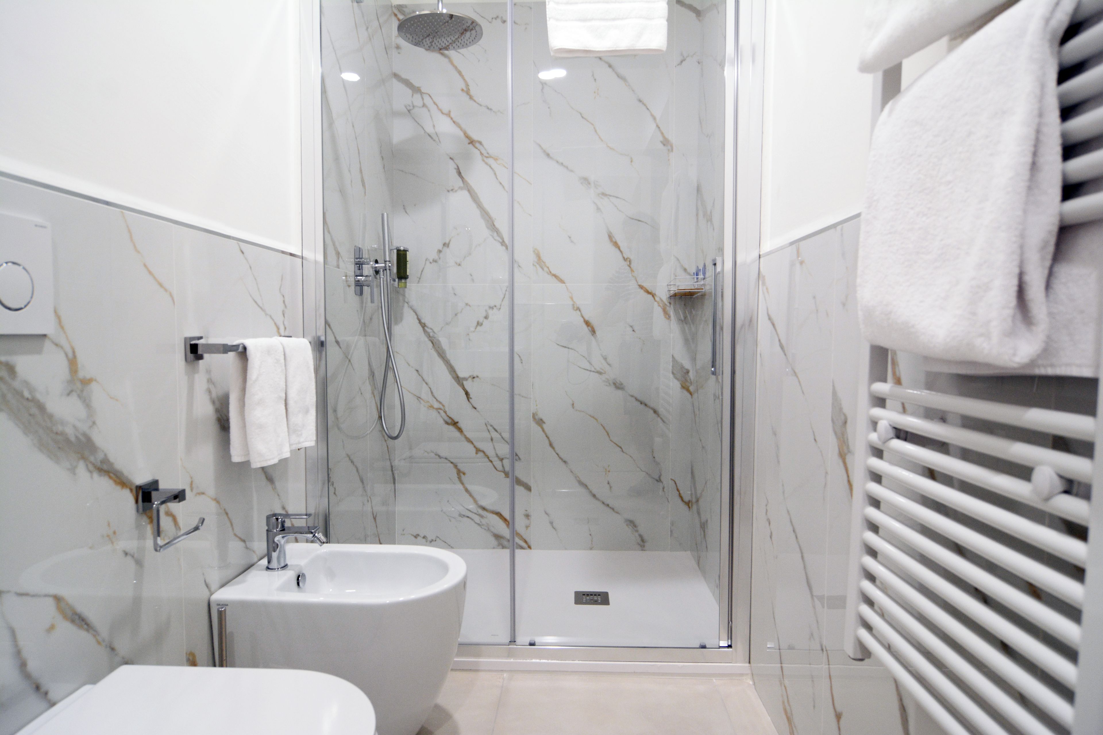 A modern bathroom with a glass-enclosed shower, a sink, and a towel rack.