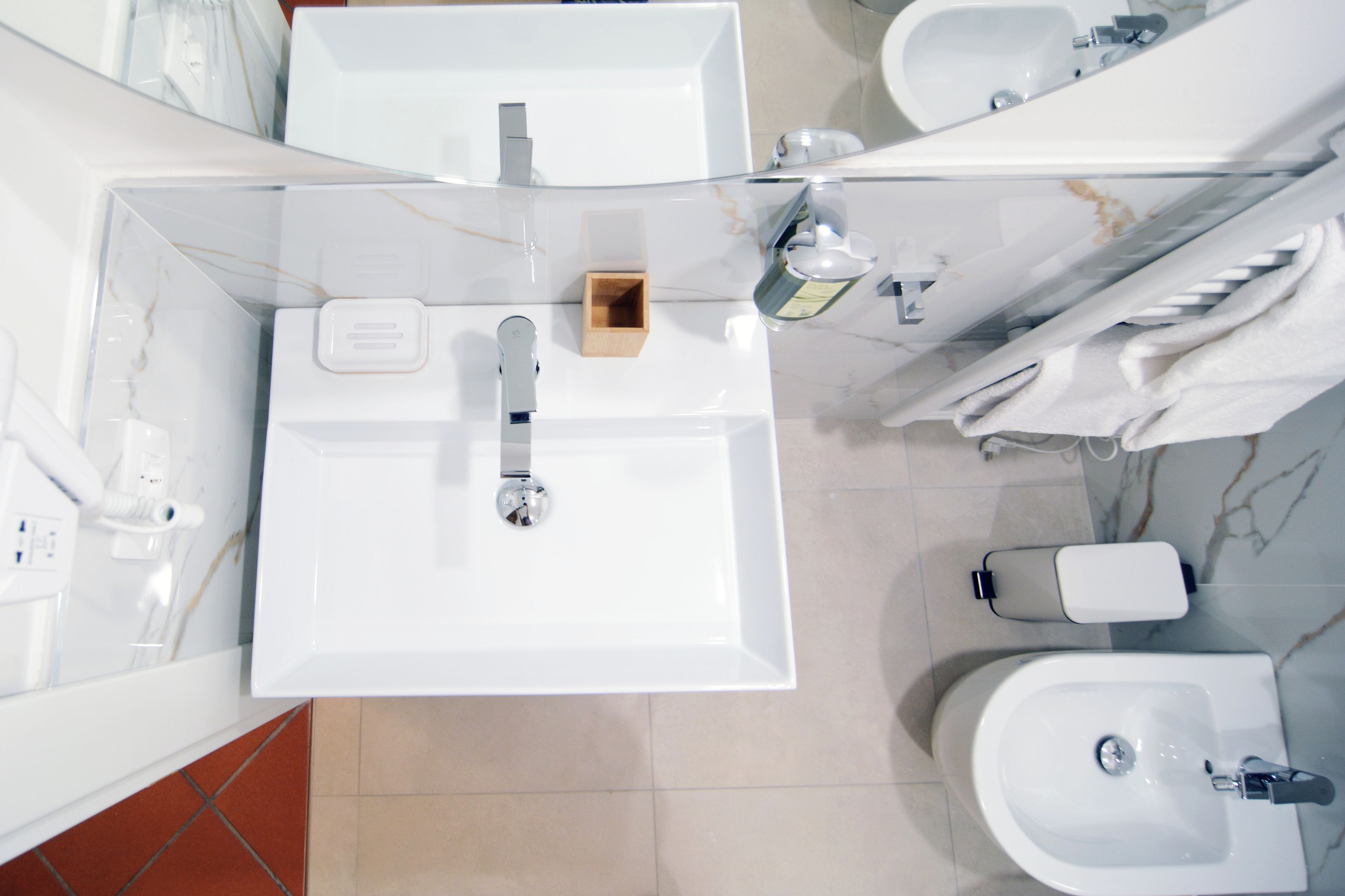 Ein modernes Badezimmer mit einem großen Spiegel, einem Waschbecken, einem Bidet und einer Toilette.