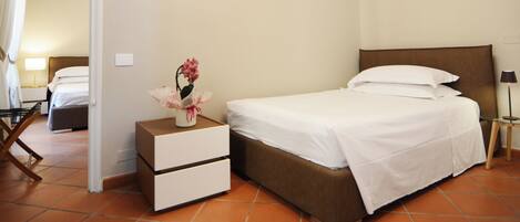 A hotel room with a bed, a nightstand with drawers, a lamp, and a chair.
