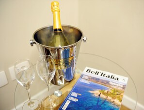 A bottle of champagne in a metal bucket, two empty wine glasses, and a magazine titled 'Bell'Italia' on a table. - Residenze Strozzi Firenze (Florence)