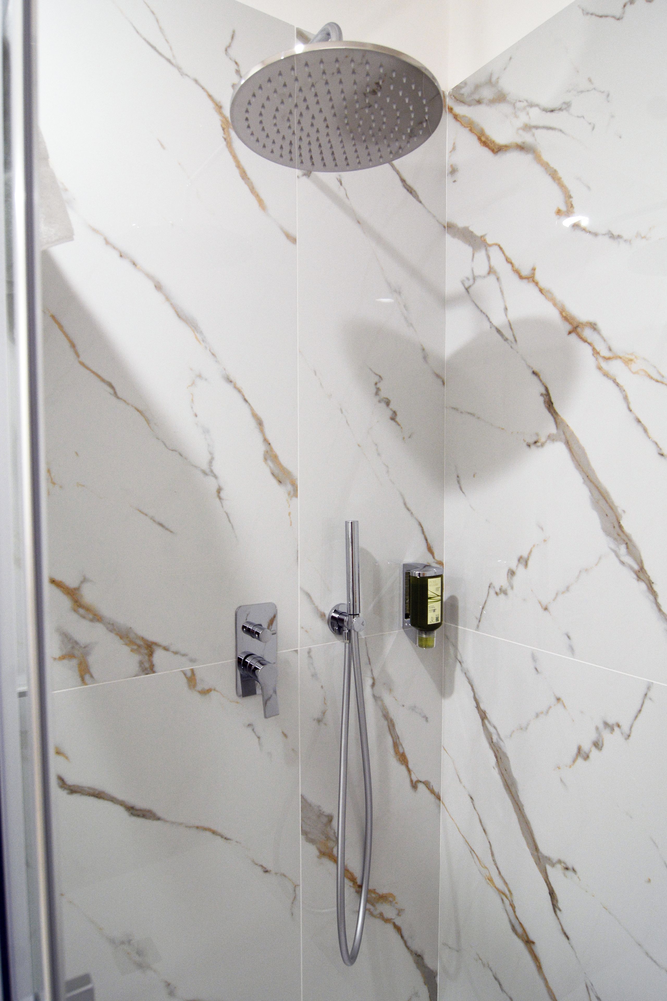 A shower with a handheld showerhead and a wall-mounted control panel.