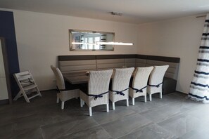 A dining area with a long table, four wicker chairs, a bench, a mirror, and a striped curtain. - Dream breeze "Dreaming under thatch" (Ostseebad Rerik)