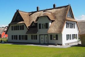 A traditional house with a thatched roof, white walls, and multiple windows. - Dream breeze "Dreaming under thatch" (Ostseebad Rerik)
