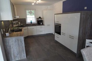 A modern kitchen with white cabinets, a built-in oven, and a coffee machine. - Dream breeze "Dreaming under thatch" (Ostseebad Rerik)