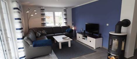 A modern living room with a sofa, coffee table, TV stand, and a fireplace.
