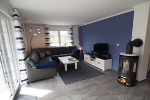 A modern living room with a sofa, coffee table, TV stand, and a fireplace. - Dream breeze "Dreaming under thatch" (Ostseebad Rerik)