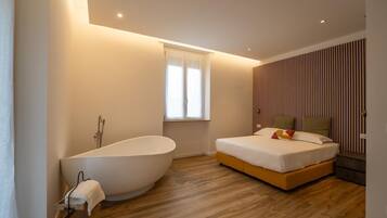 Une chambre moderne avec une baignoire sur pieds, un lit agrémenté de plusieurs coussins et une fenêtre avec des rideaux.