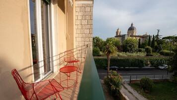 A balcony with red metal chairs and a view of a historic building with domes.