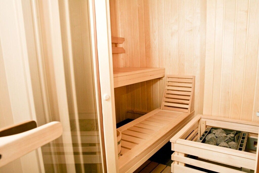 Un sauna avec des bancs en bois et un banc doté d’un siège.