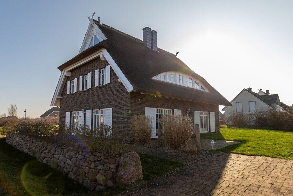 A two-story house with a steeply pitched roof, a stone foundation, and a brick exterior.