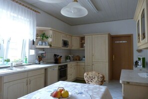 A kitchen with a dining table, a microwave, and cabinets. - Holiday apartment with 2 bedrooms (Dessau-Roßlau)