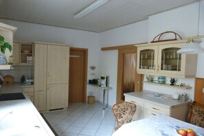 A kitchen with cabinets, a dining table with chairs, and a small side table with a microwave. - Holiday apartment with 2 bedrooms (Dessau-Roßlau)