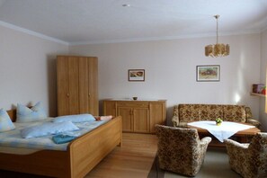 Une chambre à coucher comprenant un lit, une armoire, un canapé et une petite table sur laquelle est posé un vase.