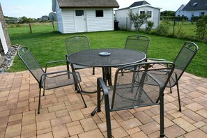 A patio with a round metal table and four chairs, surrounded by a brick patio. - House Baltic Sea Beach (3) (Dranske \/ OT lancken)