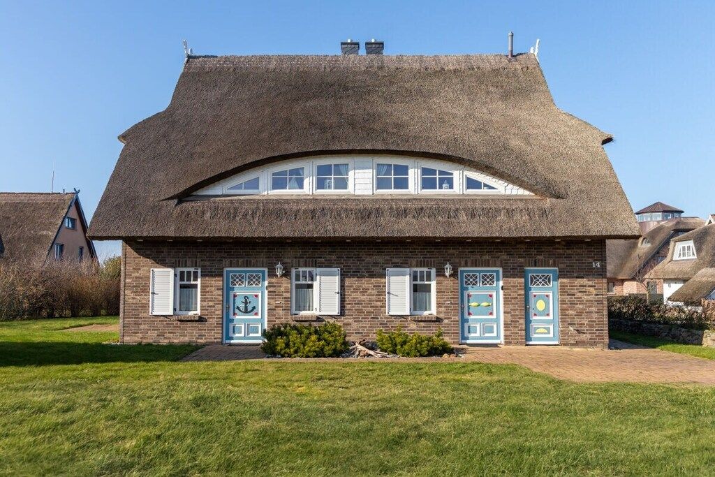 Ein traditionelles Haus mit einem Reetdach, zahlreichen Fenstern und Türen mit dekorativen Mustern.