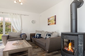A living room with a sofa, a coffee table, and a wood-burning stove. - House Baltic Sea Beach (3) (Dranske \/ OT lancken)