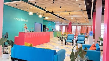 A modern interior with a reception desk, blue sofas, and potted plants.