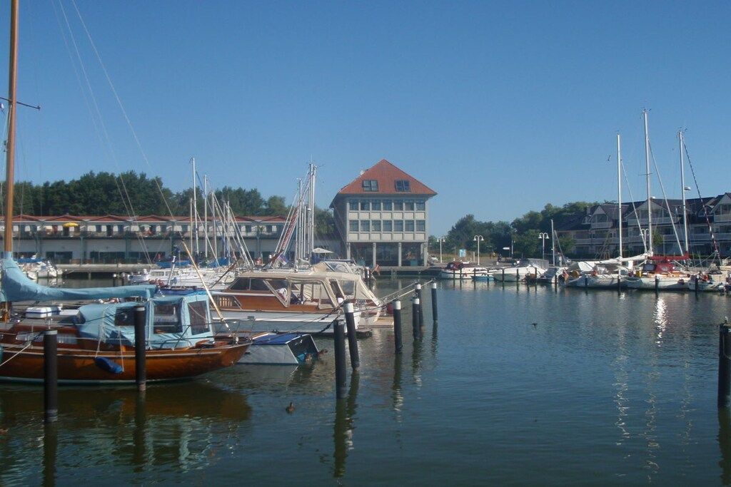 A marina with boats docked, a building with a red roof, and a clear sky.