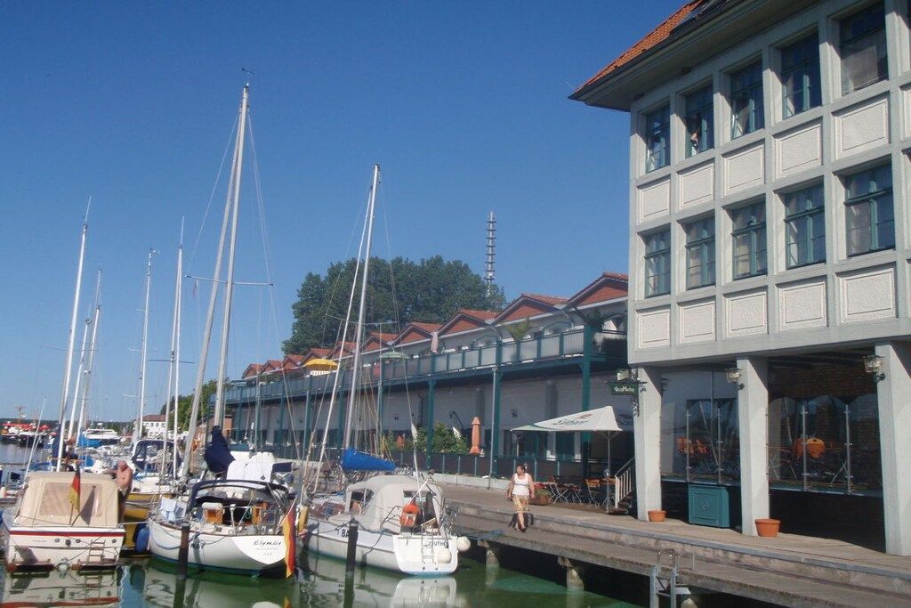 Een jachthaven met aangemeerde boten, een gebouw met grote ramen en een heldere lucht.